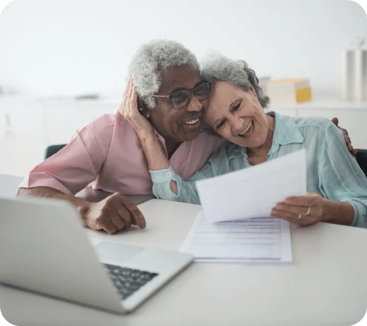Two old persons with a portatil hugging each other